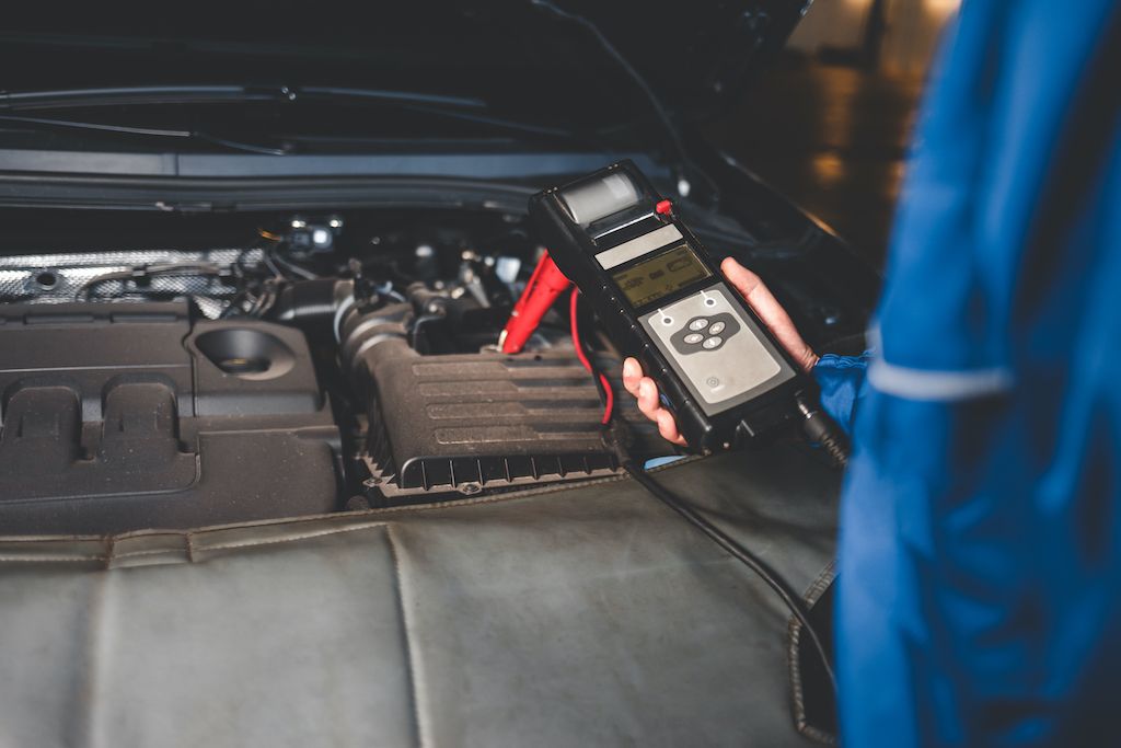 auto-mechanic-checks-car-battery-status-checking.jpg