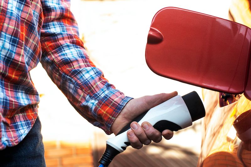 male-stands-by-an-electric-car-and-holds-a-charger.jpg