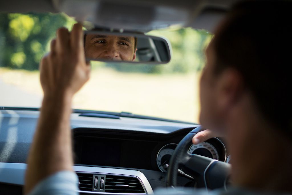 man-adjusting-mirror-in-car.jpg